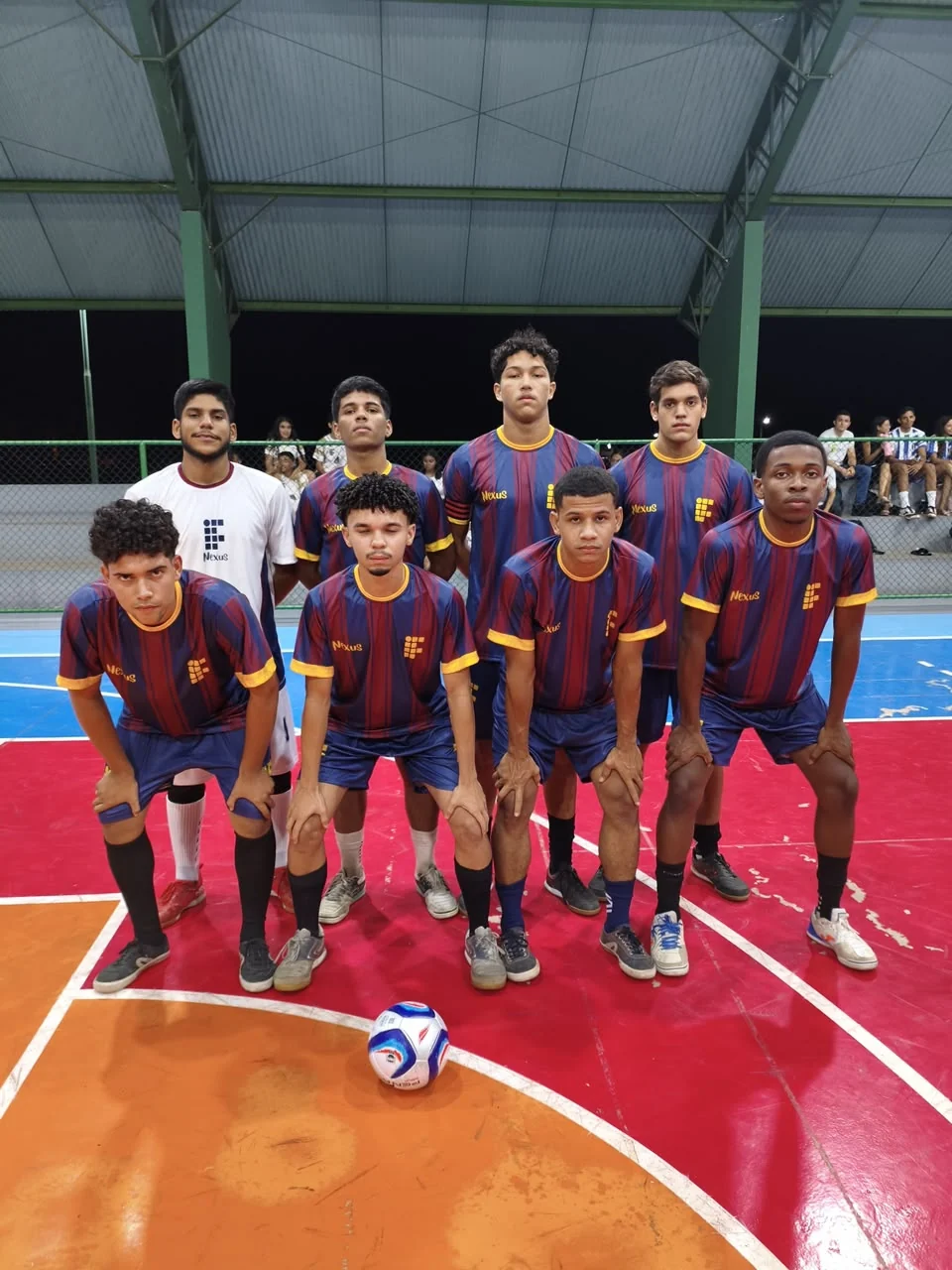 Oito jogadores reunidos para uma foto de equipe na quadra de futsal